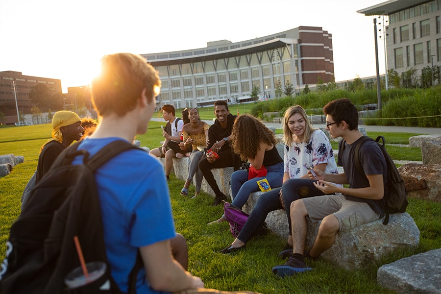 students talk sitting on stones at UMass Boston.