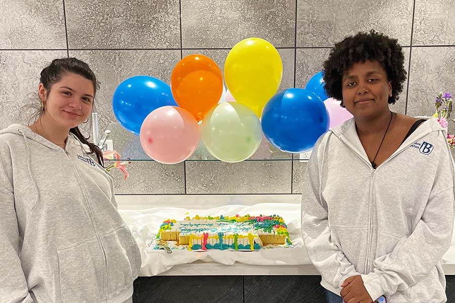 two female students with a birthday cake for March