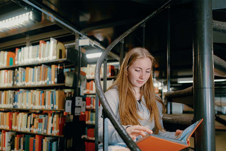 Healey library stairs and student sitting on spiral stair case with long hair reading a book!