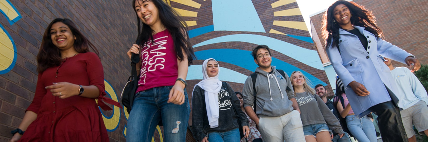 students hanging walking outside in front of UMass Boston  Beacons signage