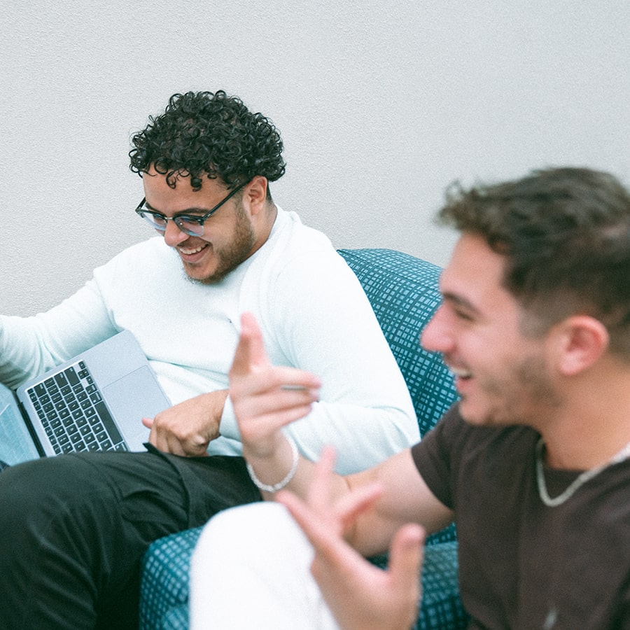 2 male students fist bumping one with laptop