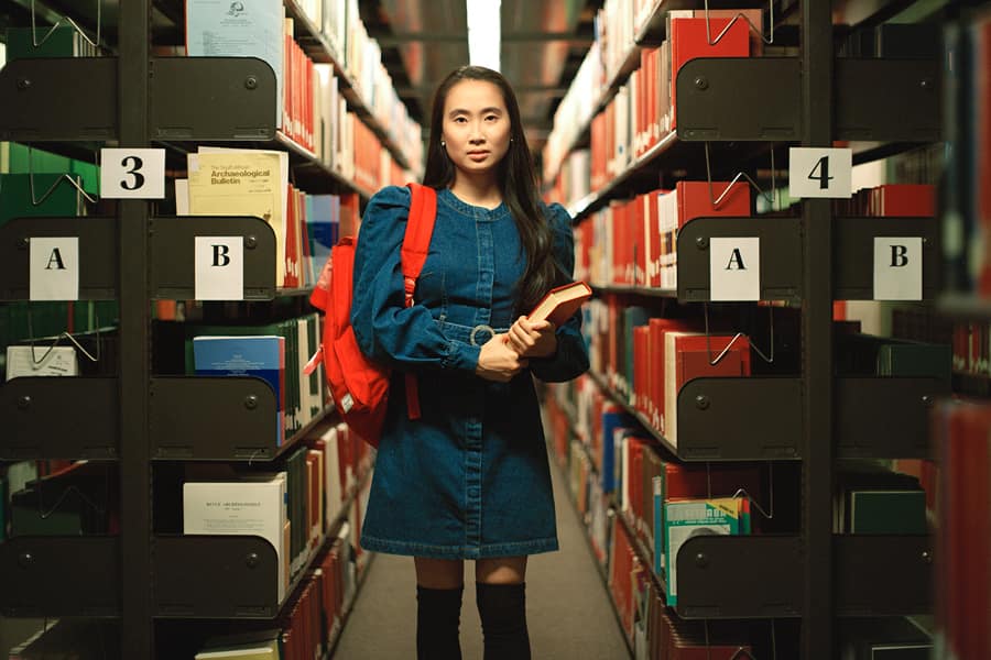 Student holds book in stacks.