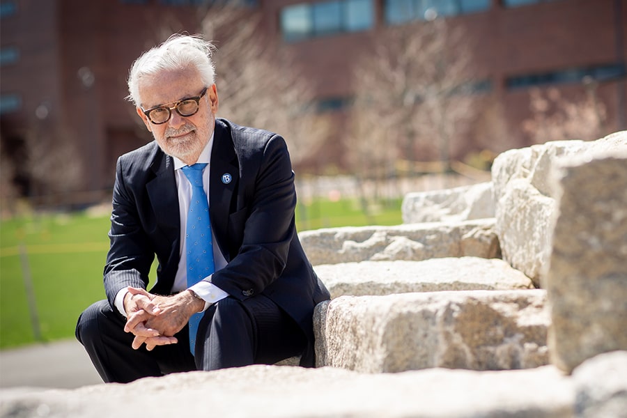 Chancellor sits on stones in the quad.