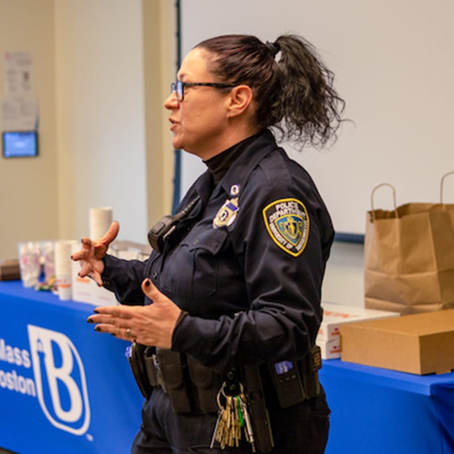 Female police officer speaks at an event at a table.