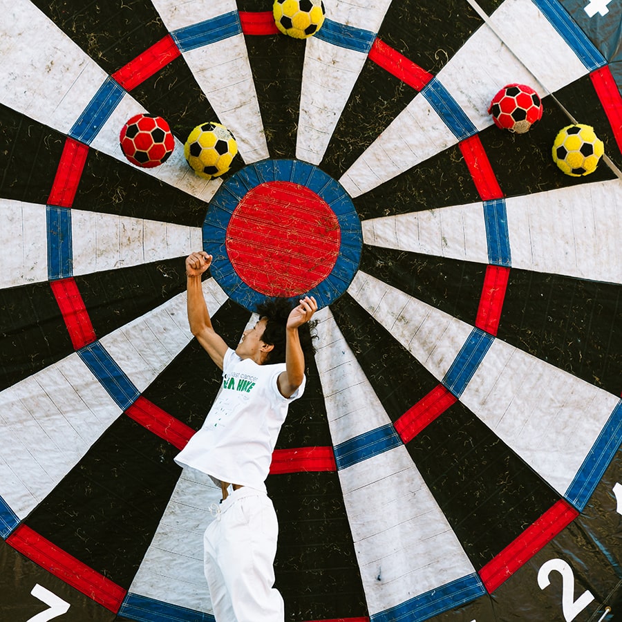 student jumps in air against a giant velcro wheel with balls sticking to it