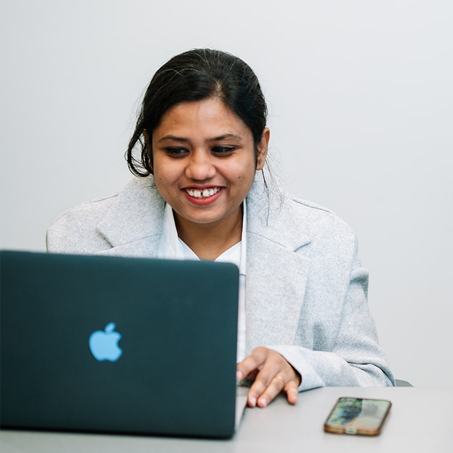 student works on laptop indoors at a table.