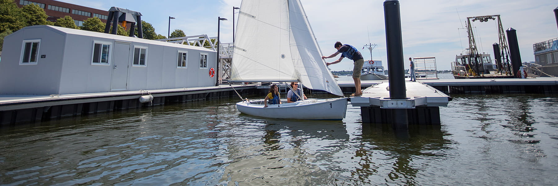 People getting into a sailboat at the dock.
