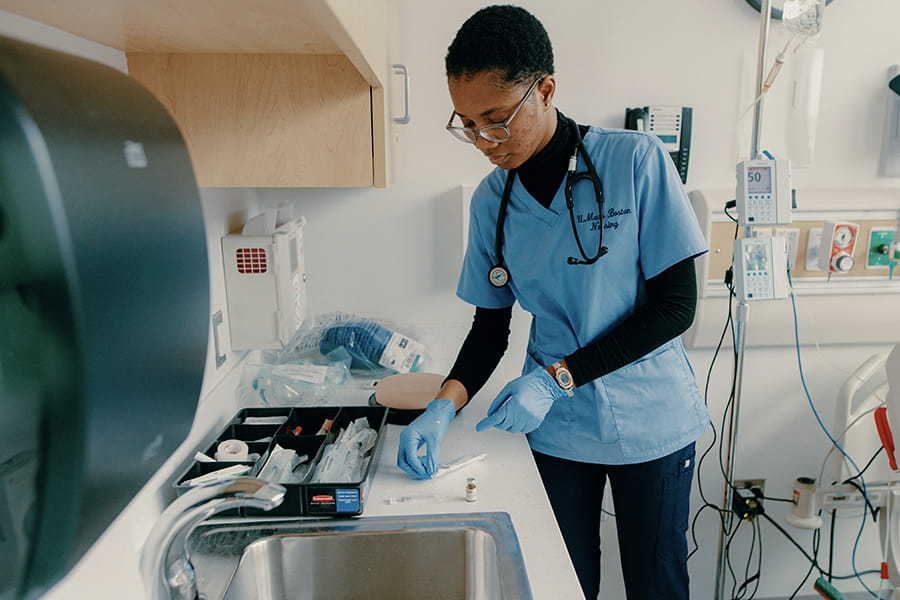 Nursing student examines equipment in lab.