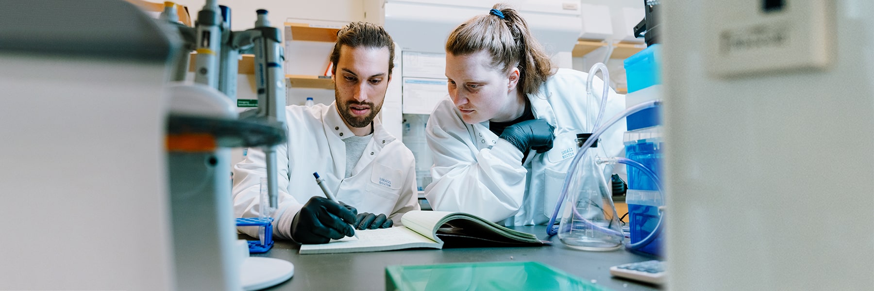 Two scientists wearing lab coats collaborate in the ISC web labs.