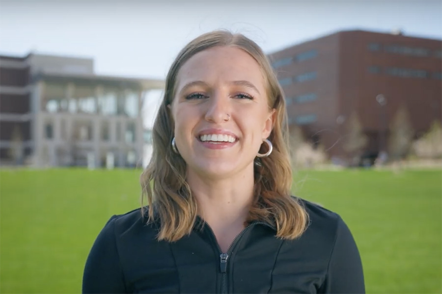 UMass Boston student Olivia standing on the quad smiling